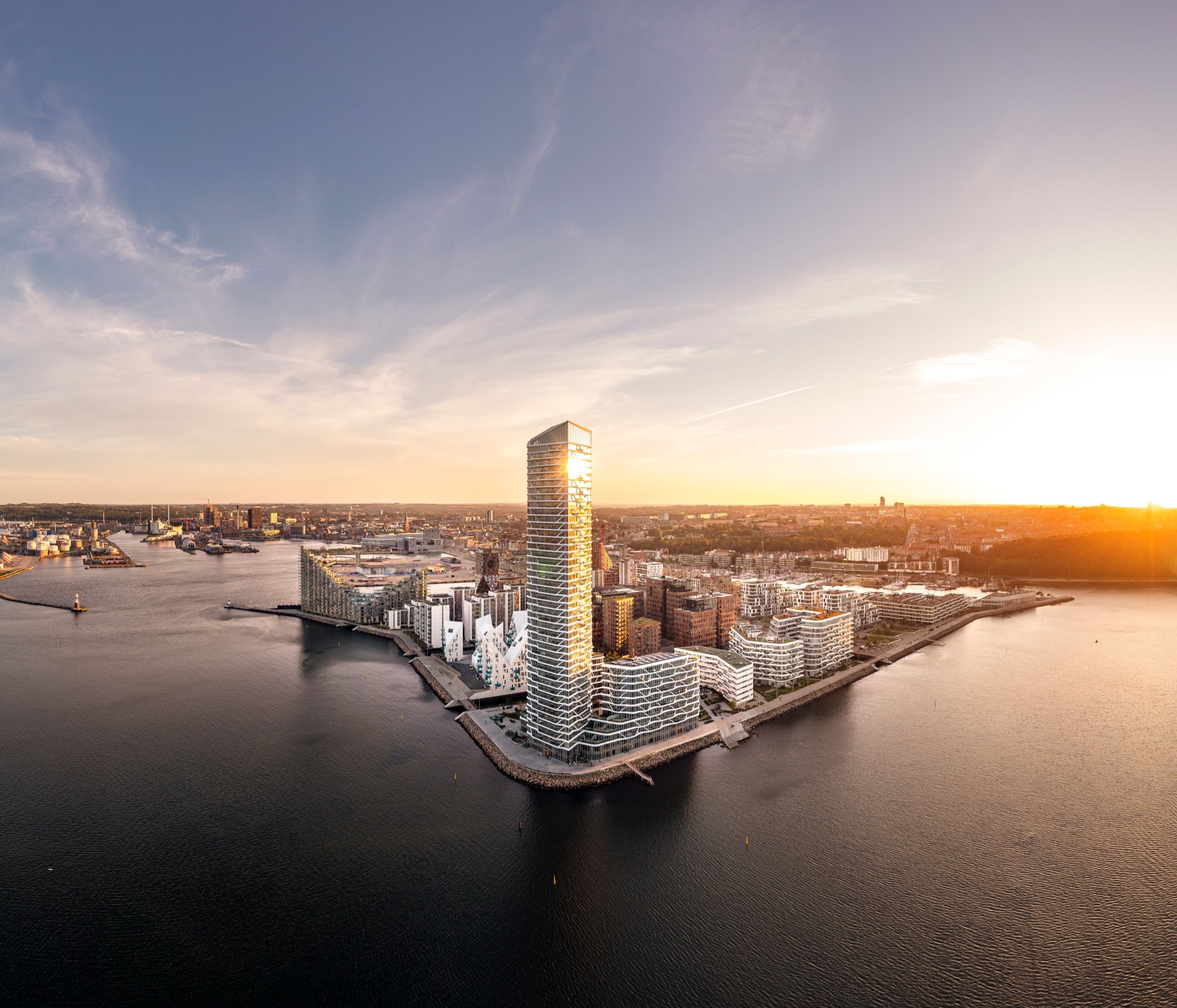 Aarhus Ø at sunset seen from above, the Lighthouse tower rising over the harbour apartments with the bay behind