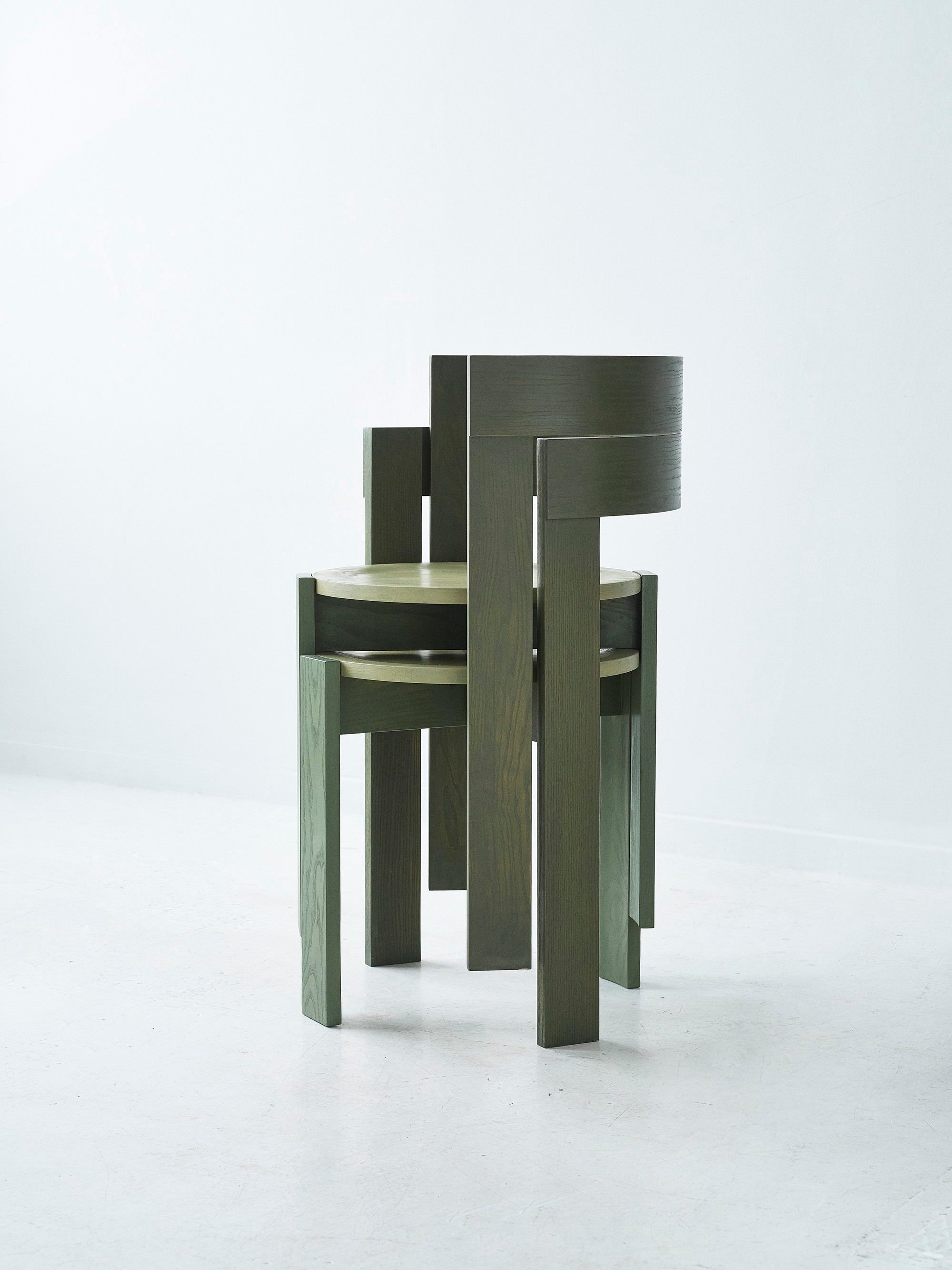 Two olive-green ash chairs from the Børsstolen series stacked on a pale floor